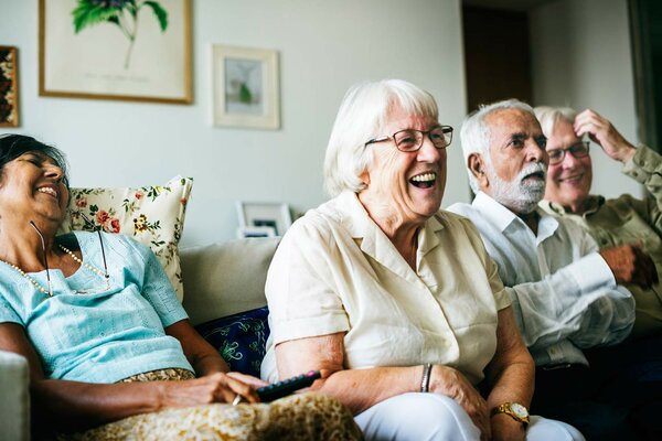 Elderly men and women sitting on a couch smiling