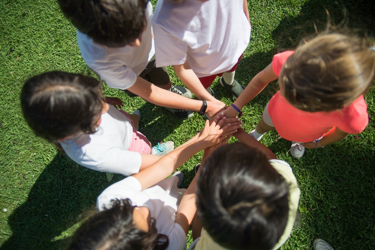 Image shows an arial view of children joining hands